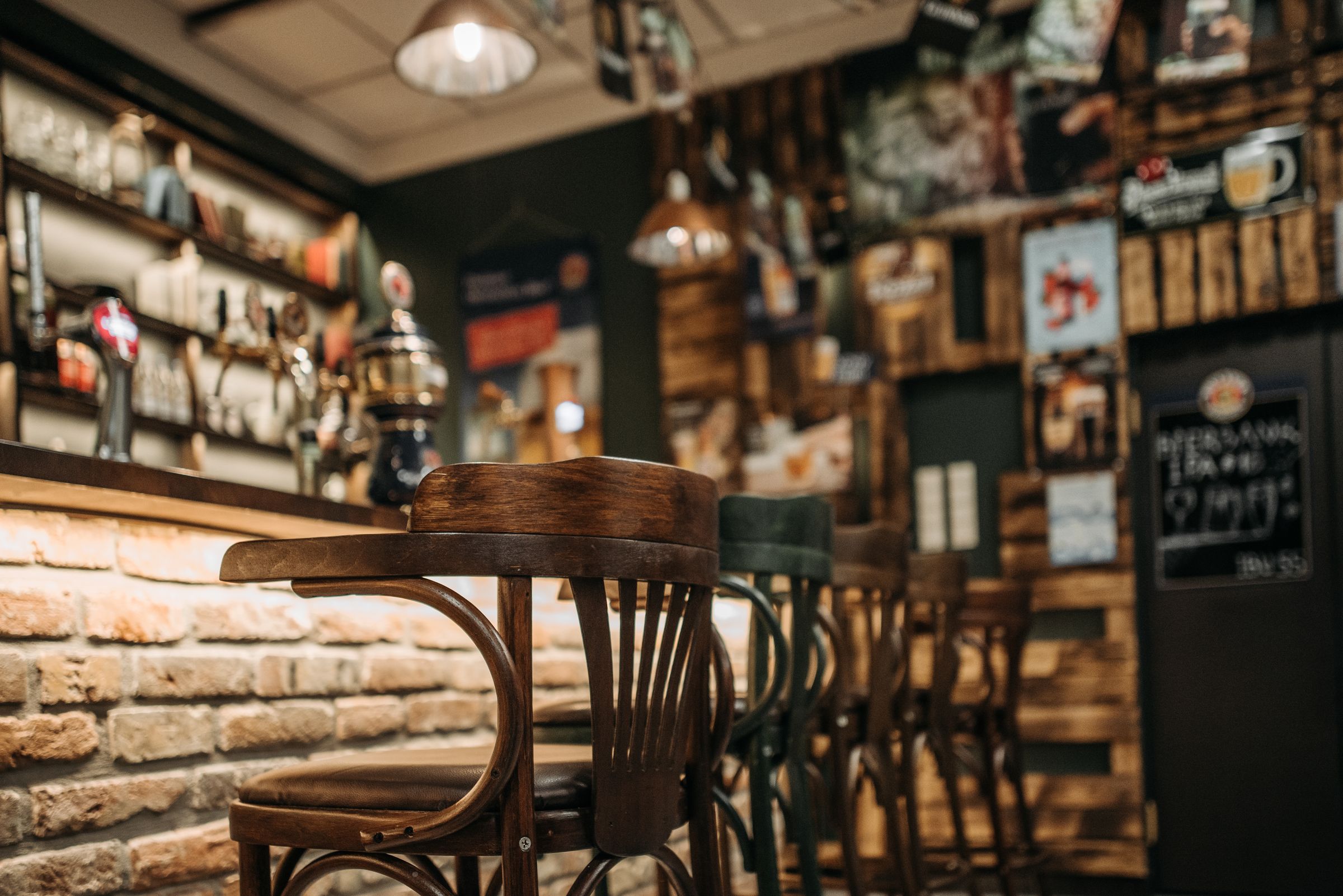 The warm, wood-and-brick bar room of a neighbourhood bar and grill, stools pulled up to the counter
